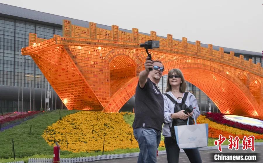 2019年4月，北京奥林匹克公园内，以“一带一路”倡议为语境的大型艺术作品“丝路金桥”主题景观点亮灯光，吸引游客拍照。<a target='_blank' href='/'>中新社</a>记者 贾天勇 摄