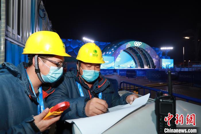图为颁奖广场电力保障团队成员在北京颁奖广场记录电力设备运行数据。张博宁 摄