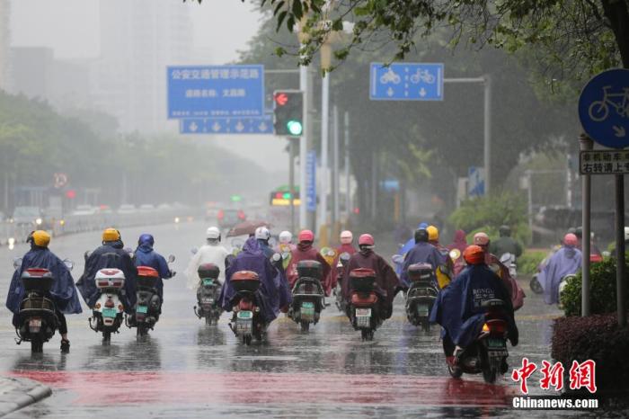 资料图：强降雨袭击广西柳州市，市民身披雨具在路上骑行。 蒙鸣明 摄