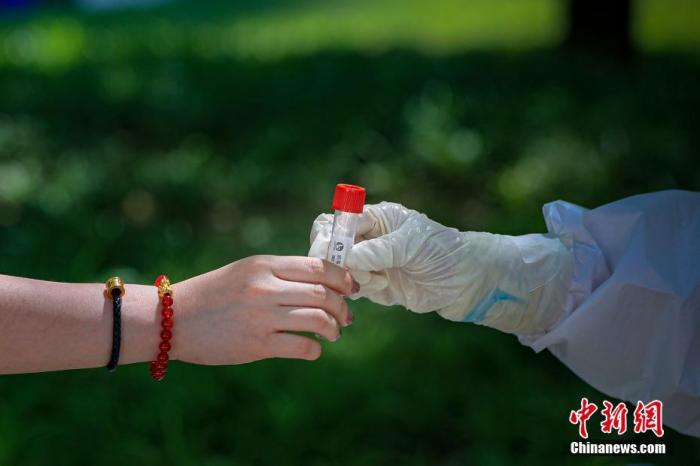 图为5月22日，一位北京市民将自己的病毒采样管交给医护人员。 <a target='_blank' href='/'>中新社</a>记者 贾天勇 摄