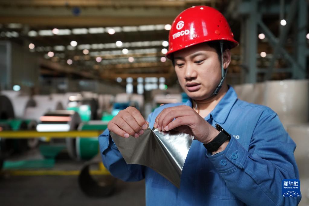 3月31日,在中国宝武太钢不锈钢精密带钢有限公司,工作人员廖席展示用手撕开超薄精密不锈带钢。新华社记者 詹彦 摄 article_img