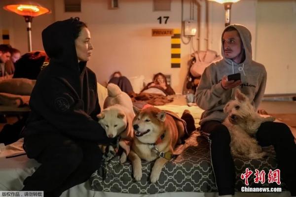 图为在乌克兰首都基辅，一对夫妇和他们的狗在空袭警报期间坐在酒店的地下停车场里。