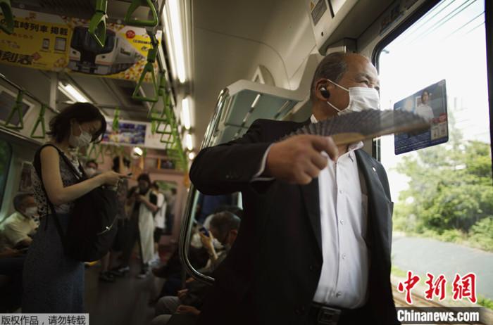 2022年6月27日,一名男子在东京乘坐火车时使用扇子扇风。日本政府27日警告东京地区可能出现电力短缺,并呼吁民众节约能源。 article_img