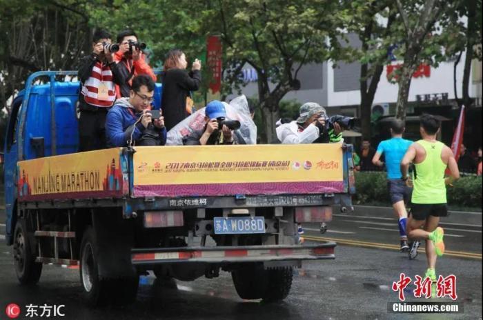 资料图：摄影记者们集体乘坐一辆卡车拍摄马拉松。图片来源：东方IC