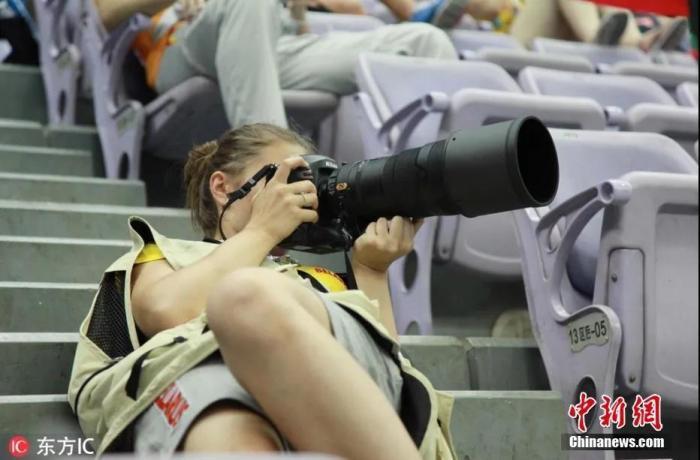 资料图：一名外国女记者在拍摄青奥会男子蹦床比赛。图片来源：东方IC