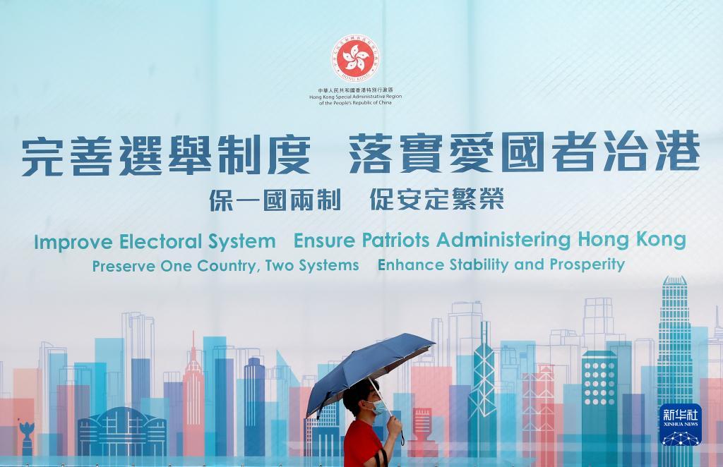 一名香港市民从“完善选举制度 落实爱国者治港”巨幅海报前经过(2021年3月31日摄)。新华社记者 吴晓初 摄
