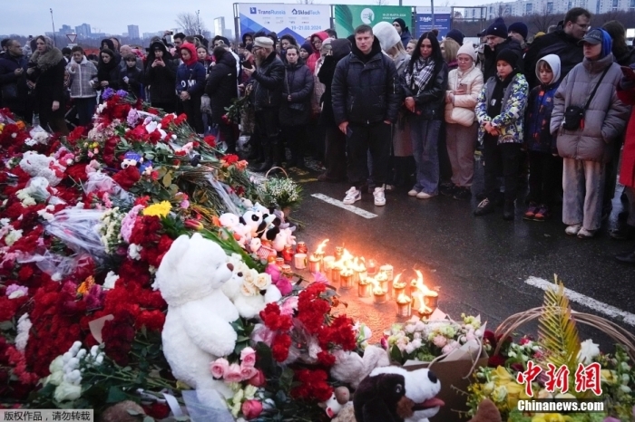 当地时间3月23日，俄罗斯当地民众前往遭受恐怖袭击的音乐厅，在围栏外面献上鲜花与玩偶，悼念遇难者。

当地时间3月22日晚，俄首都莫斯科近郊克拉斯诺戈尔斯克市一音乐厅发生恐袭事件。截至目前，此次恐怖袭击已导致至少143人死亡，另有超百人受伤。图为民众在事发现场进行悼念。